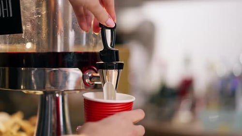 Closeup of Hands Near the Bar Counter Pouring Lemonade Into Red Paper Glass