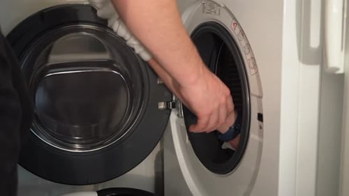 Close up: Young man empties washing into laundry basket