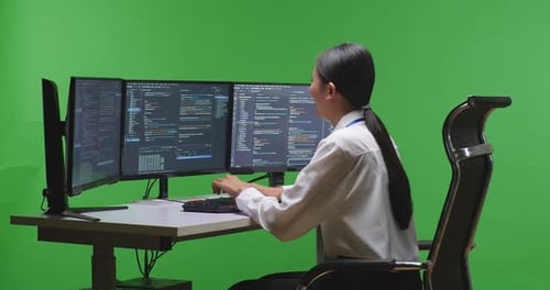 Asian Woman Developer Using Computer To Write Code With Multiple Screens In Green Screen