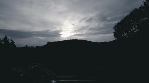 Silhouette eines Hügels bei Sonnenuntergang mit vorbeiziehenden Wolken
