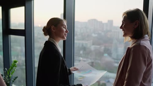 Business Women Discussing Data by Office Window