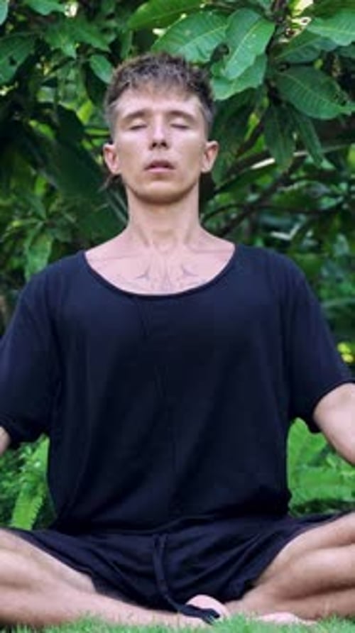 Yoga Breathing and Meditation of Young Man on Retreat Sitting in Green Nature