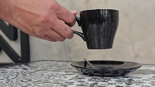 Man picking up the coffee cup in cafe