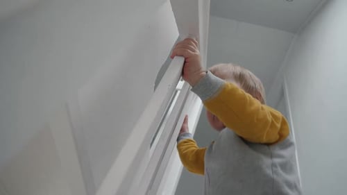Child Climbing White Stairs Holding Handrail
