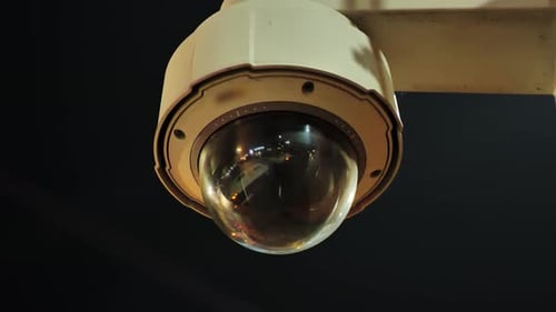 Überwachungskamera mit reflektierendem Objektiv, das die Lichter der Stadt im Dunkeln einfängt, 4K