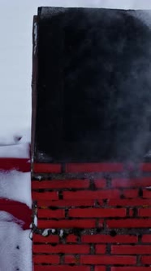 Red Brick Chimney Emitting Smoke Against Snowy Background