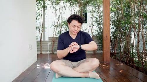 Asian man looking at his smartwatch to monitor the heart rate