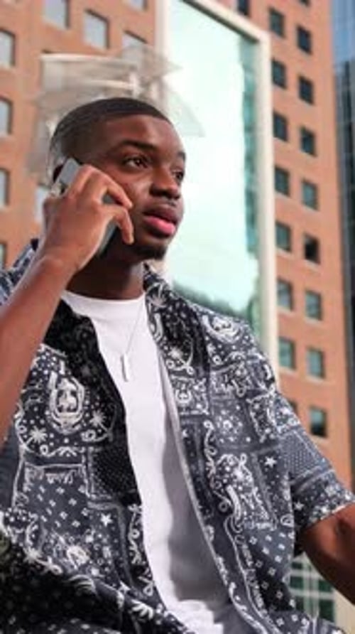 Young Man Answers Phone in City Setting