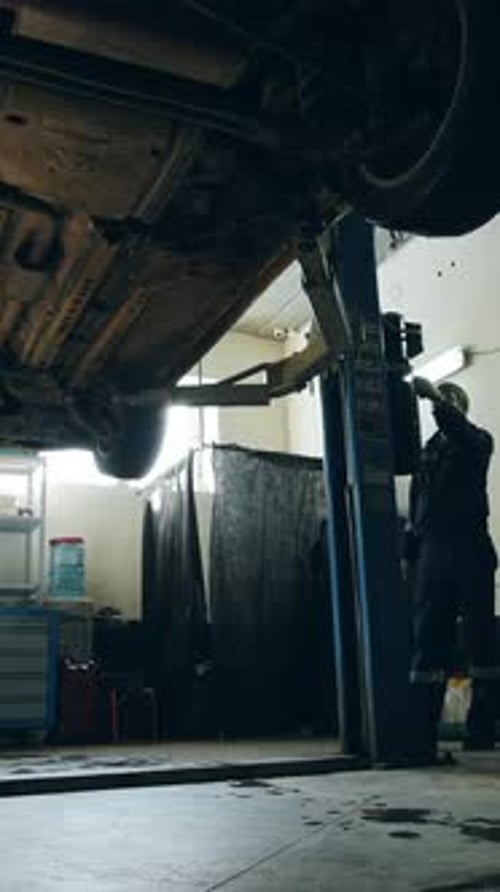 Car is Lowered in Automobile Service for Checking Worker Repairs Detail