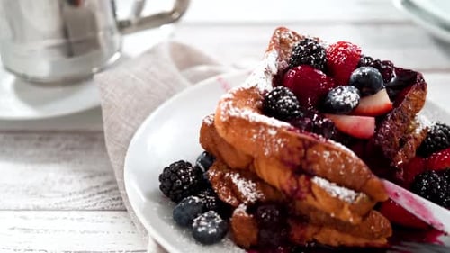 Eating Freshly Made French Toast Garnished with Mix Berry Compote and Powder Sugar