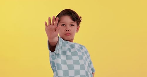 Young boy, face and stop in tshirt on studio background for warning, protest and wrong action