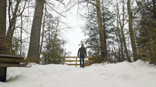 Young Male Hiker with backpack walks away from view point in winter forest. Static Shot (4K)