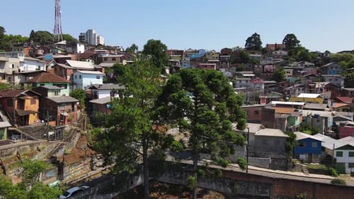 Slow upward drone shot revealing a small Brazilian slum (favela) with colorful shacks and small hous