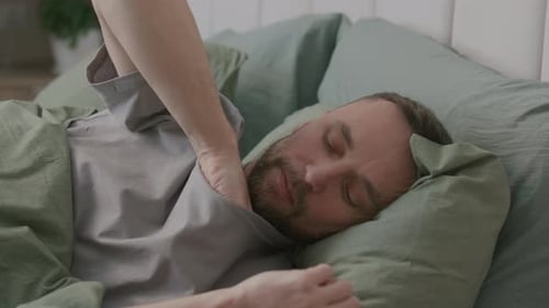 Man Sick in Bed Measuring Temperature with Thermometer