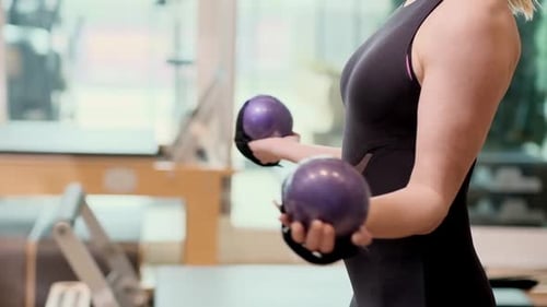 Woman Doing Bicep Curls with Pilates Weights