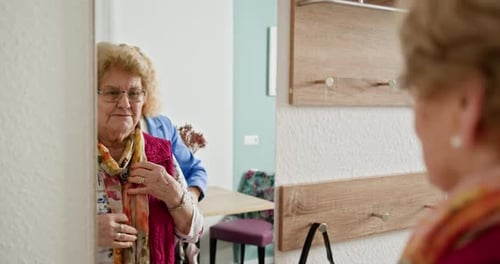 Woman Helping Senior Woman with Scarf and Jacket