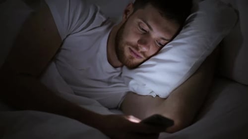 Man Lies in Bed at Night Using Smartphone