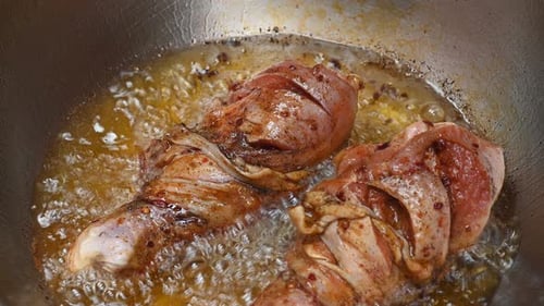 Sizzling oil frying two pieces of chicken to golden brown in a stainless steel pan; Frying Chicken D