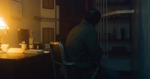 Man sits alone in his apartment, drinks and thinks.