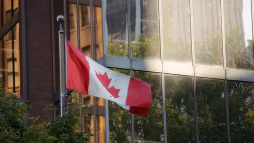 Canadian Flag Waving near Glass Office Building