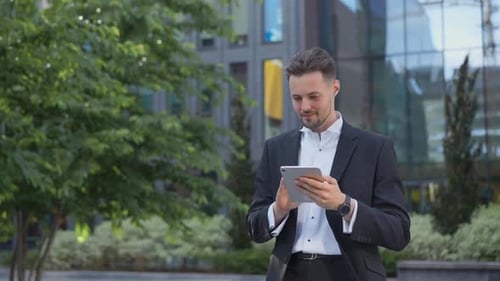 Stylish Handsome Businessman Holding Tablet Reading Email Stands on Street Smiling Writes Message