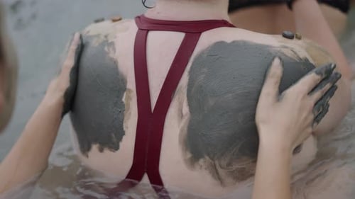 Teenage Womans Hands Putting Mud on a Womans Back