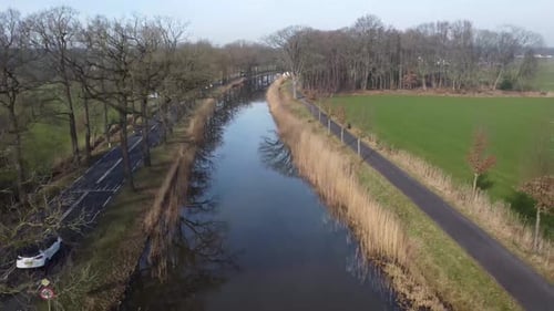 Drone shot of dutch landscape with canal and road alongside.