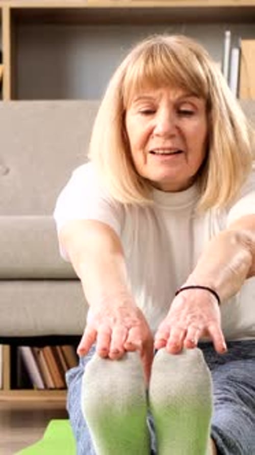 Senior Woman Stretching on Yoga Mat Indoors
