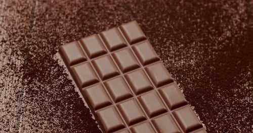 Rich Milk Chocolate Bar on Cocoa Powdered Surface Closeup