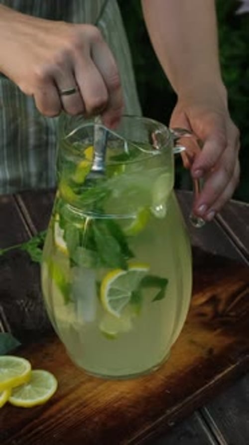 Refreshing Lemonade With Mint Stirred on Wooden Table