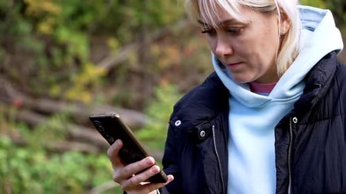 Eine junge Frau mit einem Handy in der Hand schreibt eine Online-Textnachricht