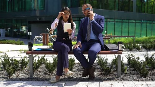 Businessman Talking on Cellphone, Businesswoman with Tablet Computer in City Attractive