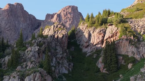Sunlight Gently Illuminating Rugged Mountain Peaks and Lush Green Slopes