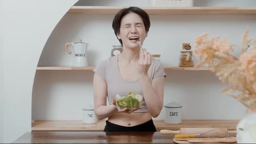 Woman Enjoys Fresh Salad in Bright Kitchen