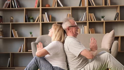 Senior Couple Doing Yoga Back to Back Indoors