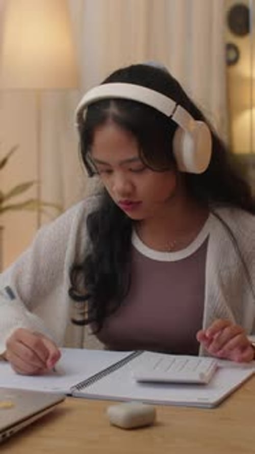 Student Studying and Taking Notes in a Notebook