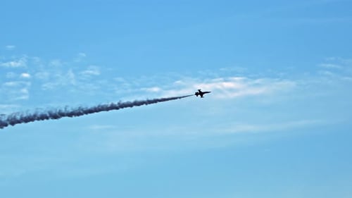 Jet Plane Flying With Smoke Trail Across Blue Sky