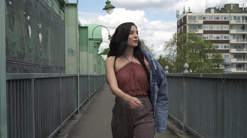 Stylish Woman Walks on Urban Bridge