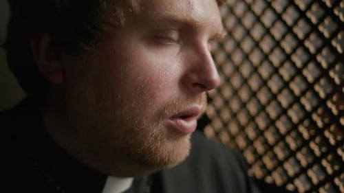 Priest Sitting inside Confessional Booth during conversation with Penitent
