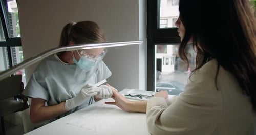 Nail Technician Filing Nails of Customer in Salon