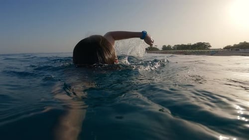Man Swim in Open Ocean Near the Beach During Sunset Golden Hour