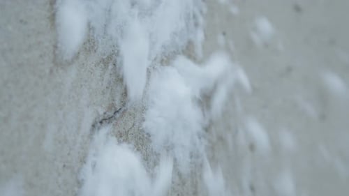 Slowmotion closeup of snowballs hiting and splashing a concrete grey wall with crack