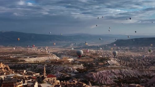 View on Ancient Goreme Town in Cappadocia with Houses and Buildings and Flying Balloons in Sky