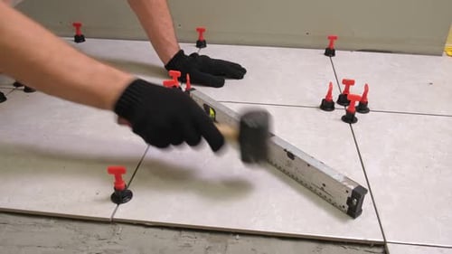 Worker Laying Ceramic Tiles on the Floor Repairman Placing White Gray Square Tiles Applying Adhesive