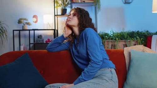 Woman Contemplating on an Orange Couch Indoors