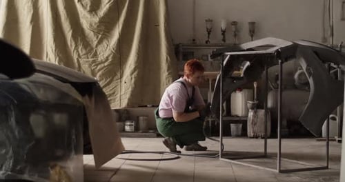 Adult Working on Car Bumper in Repair Shop