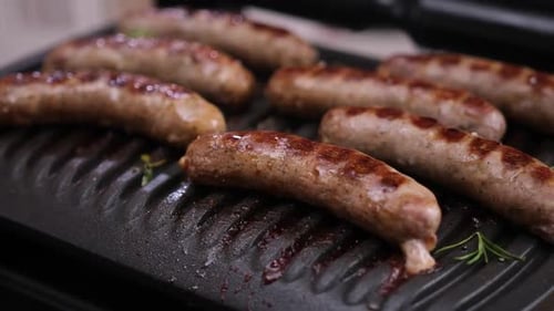 Homemade Juicy Pork Sausages with Spices Frying on Electric Grill