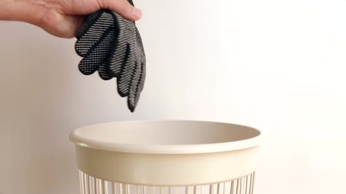 Hand Disposing of Glove in Trash Receptacle