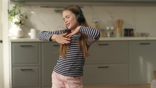 Girl Dancing and Singing with Headphones in Kitchen