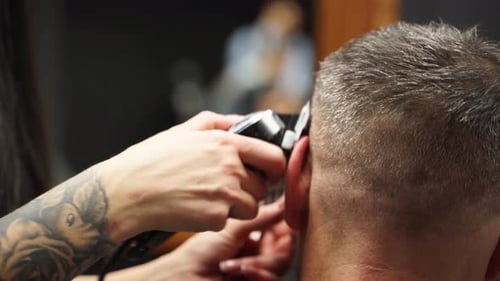 Friseurin schneidet bärtigen Männern die Haare mit einer Haarschneidemaschine im Barbershop Haarstyling und Haarschnitt für Männer
